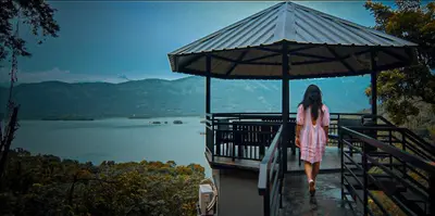 a woman walking on a dock with an umbrella at Casa Lucio Resorts in Mannārakkāt