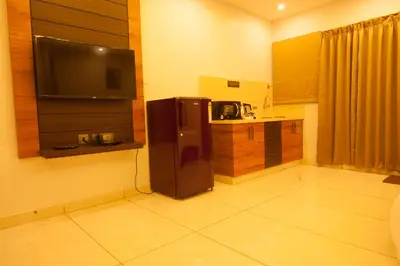 a small kitchen with a refrigerator and a microwave at MC Suites Mysuru in Mysore