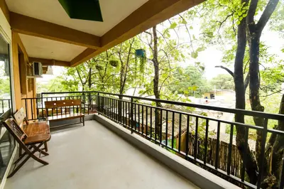 a balcony of a house with a chair and trees at SAFARI QUEST in Mysore