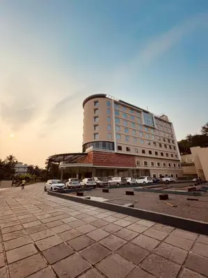 a large building with cars parked in a parking lot at Dimora Kozhikode in Kozhikode