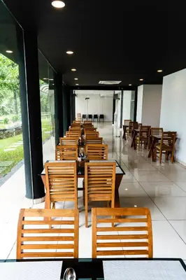 a row of wooden tables and chairs in a restaurant at S RIVER RESORTS in Cochin