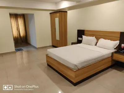 a bedroom with a large bed with a wooden headboard at Hotel Sree Gokulam Apartments in Guruvāyūr