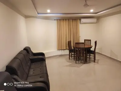 a living room with a couch and a table and chairs at Hotel Sree Gokulam Apartments in Guruvāyūr