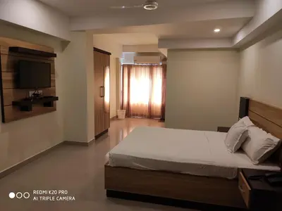 a bedroom with a bed and a flat screen tv at Hotel Sree Gokulam Apartments in Guruvāyūr
