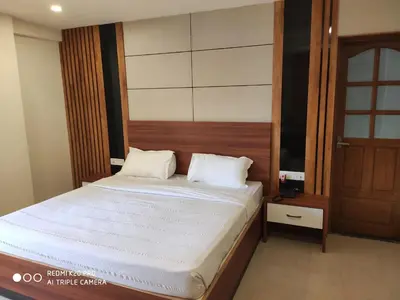 a bedroom with a large bed with a wooden headboard at Hotel Sree Gokulam Apartments in Guruvāyūr