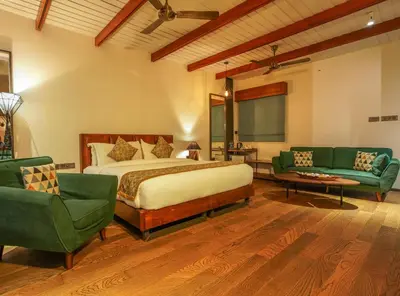 a bedroom with a bed and two green chairs at Vyna Hillock Resort in Vythiri
