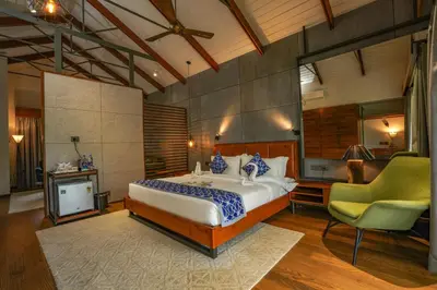 a bedroom with a large bed and a chair at Vyna Hillock Resort in Vythiri