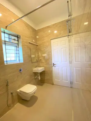 a bathroom with a toilet and a sink and a door at Avalon Stays in Ooty