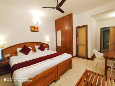 a bedroom with a large bed and a desk and a table at KTDC Tamarind, Mannarkkad in Alanallūr