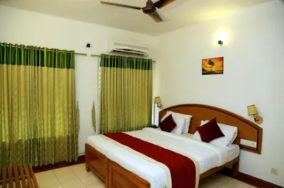 a bedroom with a large bed with green curtains at KTDC Tamarind, Mannarkkad in Alanallūr