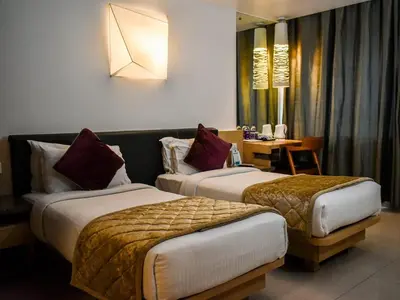 a hotel room with two beds and a table at Nexstay Asma Tower in Kozhikode