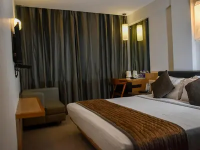 a hotel room with a bed and a chair at Nexstay Asma Tower in Kozhikode