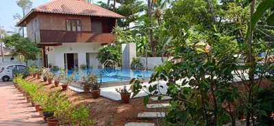 a villa with a swimming pool in front of a house at Cherai Beach Residency in Cherai Beach