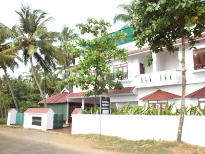 a white building with palm trees in front of it at Cherai Beach Residency in Cherai Beach