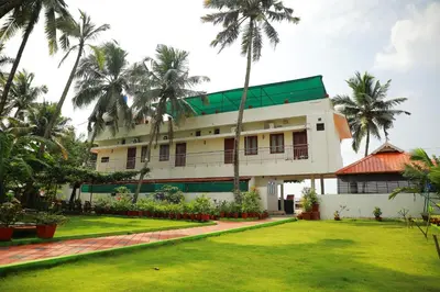 a building with palm trees in front of a yard at Cherai Beach Residency in Cherai Beach