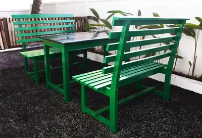 two green benches sitting next to a table at Cherai Beach Residency in Cherai Beach