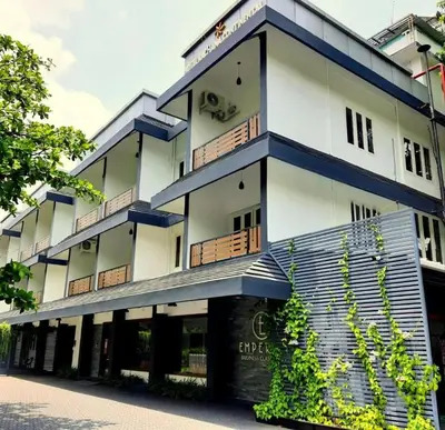 a white building with blue balconies on a street at Emperor-Hotel Rachana Continental Pvt Ltd in Kizhake Chālakudi