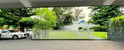 a white car parked in a parking lot with a gate at Emperor-Hotel Rachana Continental Pvt Ltd in Kizhake Chālakudi