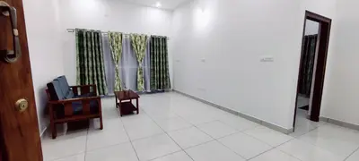a room with a chair and a table and curtains at Suvarna Elite - Premium Apartment Hotel in Mysore