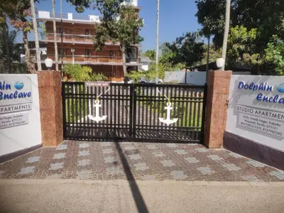 a black wrought iron gate with two signs on it at DOLPHIN ENCLAVE SERVICE STUDIO APARTMENTS in Kalpetta