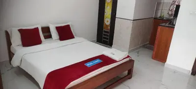 a bedroom with a white bed with red pillows at DOLPHIN ENCLAVE SERVICE STUDIO APARTMENTS in Kalpetta