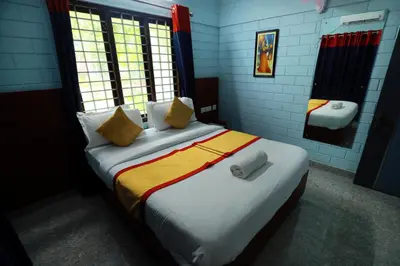 a bedroom with a large bed with yellow and white pillows at NARMADA POOl VILLA in Angādipuram