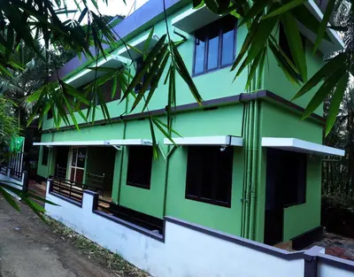 a green and white building with trees in front of it at NARMADA POOl VILLA in Angādipuram