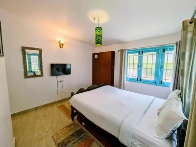 a bedroom with a bed and a tv and a window at Bohemian Hideaway by Futurve in Kodaikānāl