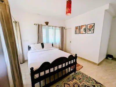 a bedroom with a bed with white sheets and a window at Bohemian Hideaway by Futurve in Kodaikānāl