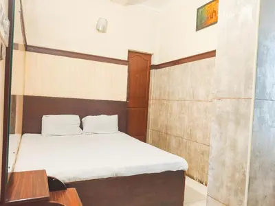 a small bedroom with a bed with white sheets at New AS Tourist Home Aluva in Cochin