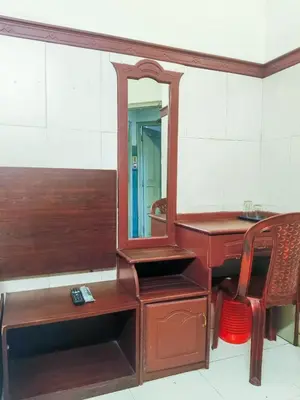 a wooden desk with a mirror next to a chair at New AS Tourist Home Aluva in Cochin