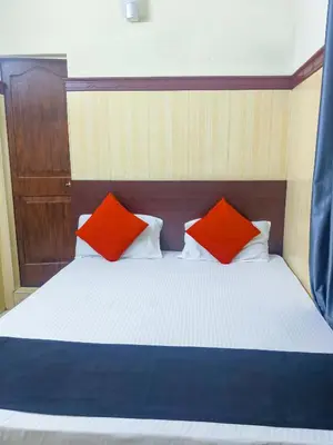 a bedroom with a bed with two red pillows at New AS Tourist Home Aluva in Cochin