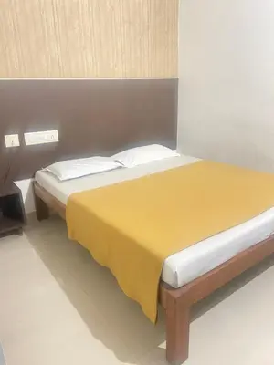 a bedroom with a bed with a yellow blanket on it at Star Residency in Mysore