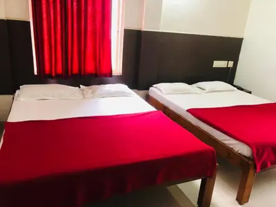 two beds in a room with red curtains at Star Residency in Mysore