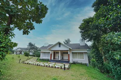 a white house with a porch in a yard at Jungle Bay Resorts & Spa in Wayanad