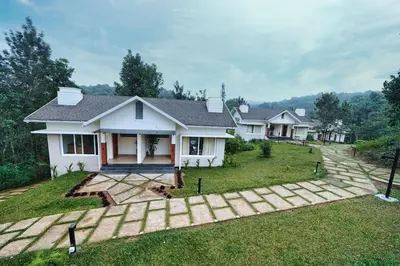 a white house with a lawn in front of it at Jungle Bay Resorts & Spa in Wayanad