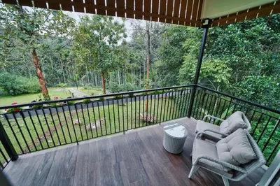 a patio with two chairs and a table on a deck at Jungle Bay Resorts & Spa in Wayanad