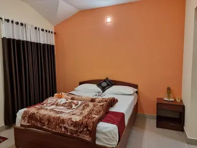 a bedroom with a large bed with orange walls at HAVEN COTTAGE in Ooty