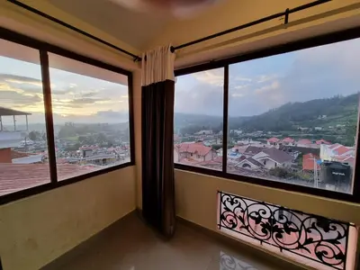a room with large windows with a view of a city at HAVEN COTTAGE in Ooty
