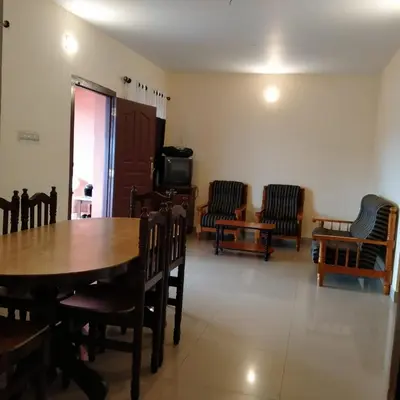 a dining room with a wooden table and chairs at HAVEN COTTAGE in Ooty