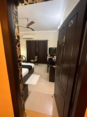 a room with a bed and a desk and a door at GD International Redfort in Nilambūr