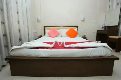 a bed with orange and pink pillows on it at Hotel Innate Inn in Alwaye