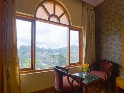 a room with a large window with a table and chairs at The Byke Sunshine Grand in Ooty