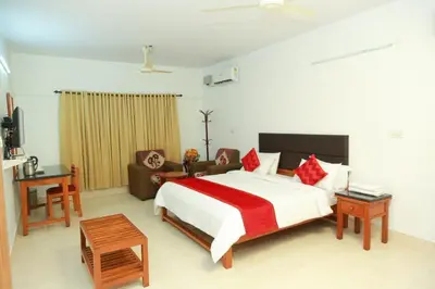 a bedroom with a large white bed and a couch at KTDC Tamarind Kondotty in Kondotti
