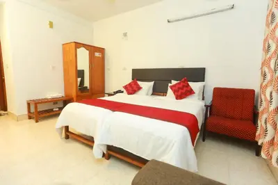 a bedroom with a large bed and a red chair at KTDC Tamarind Kondotty in Kondotti