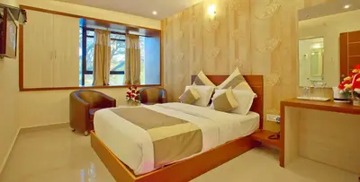 a bedroom with a large bed and a window at Aishwarya Suites in Mysore