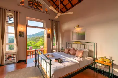 a bedroom with a bed and a large window at Zostel Homes Wayanad, Vythiri in Wayanad