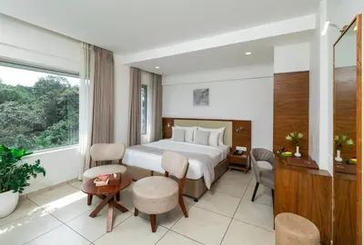 a hotel room with a bed and a table and chairs at Oshin Wayanad in Wayanad