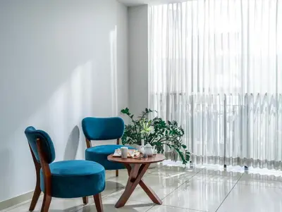 a living room with two chairs and a table and a window at Oshin Wayanad in Wayanad