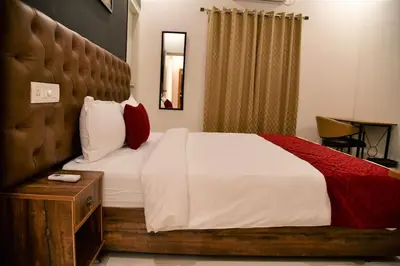 a bedroom with a large bed with white sheets and red pillows at Xcel Luxury Hotel Apartments-Home Living Redefined in Mysore